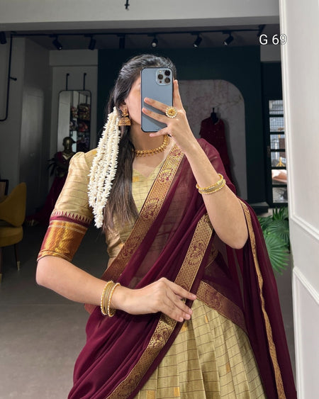 Person wearing a traditional maroon and gold saree with jewelry, taking a mirror selfie.