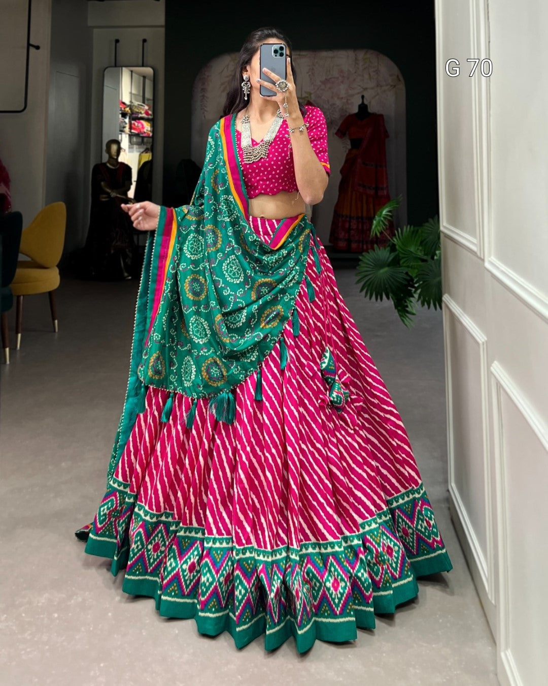Woman in a pink and green traditional outfit taking a mirror selfie.
