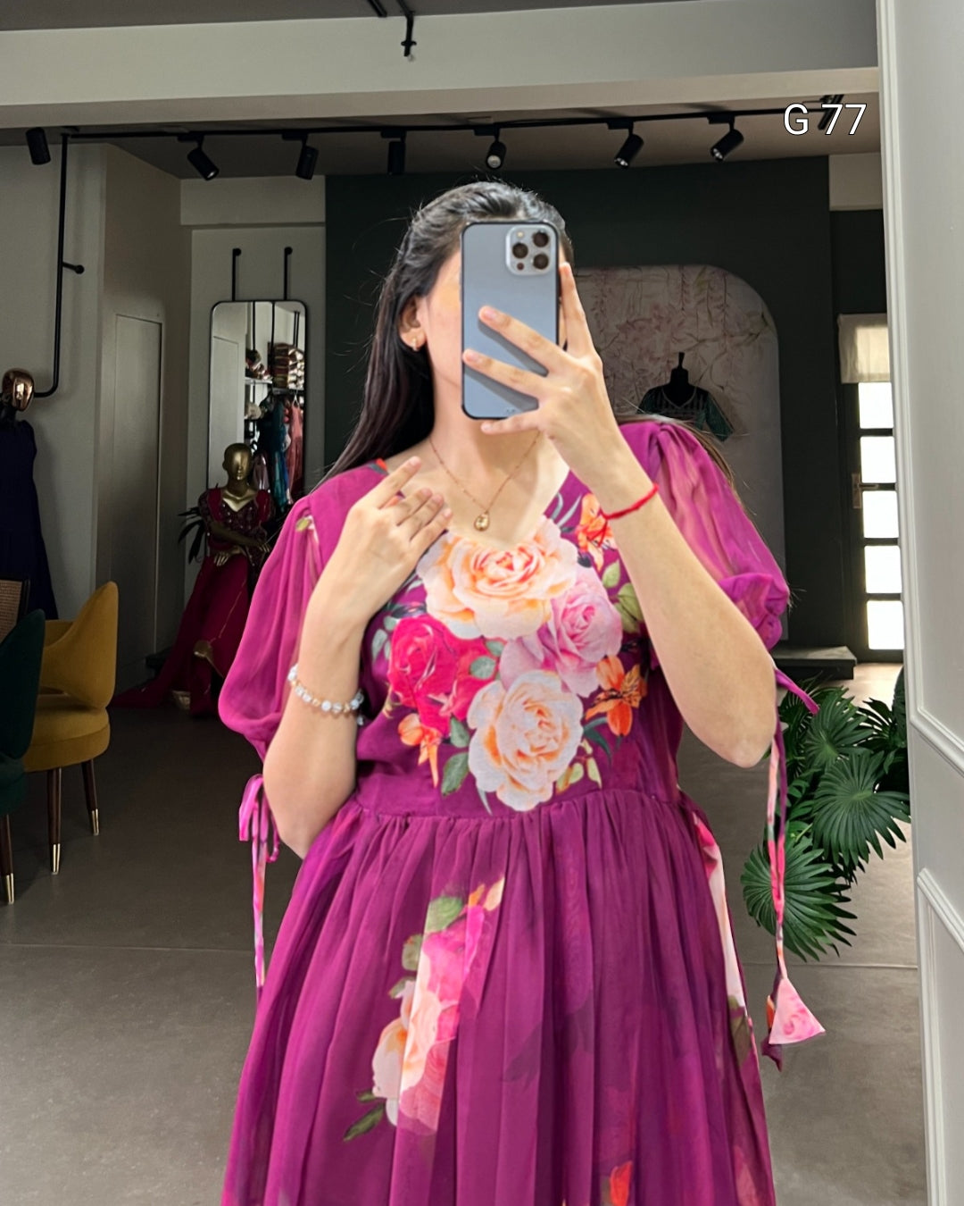 Person wearing a vibrant purple dress with floral patterns taking a mirror selfie.
