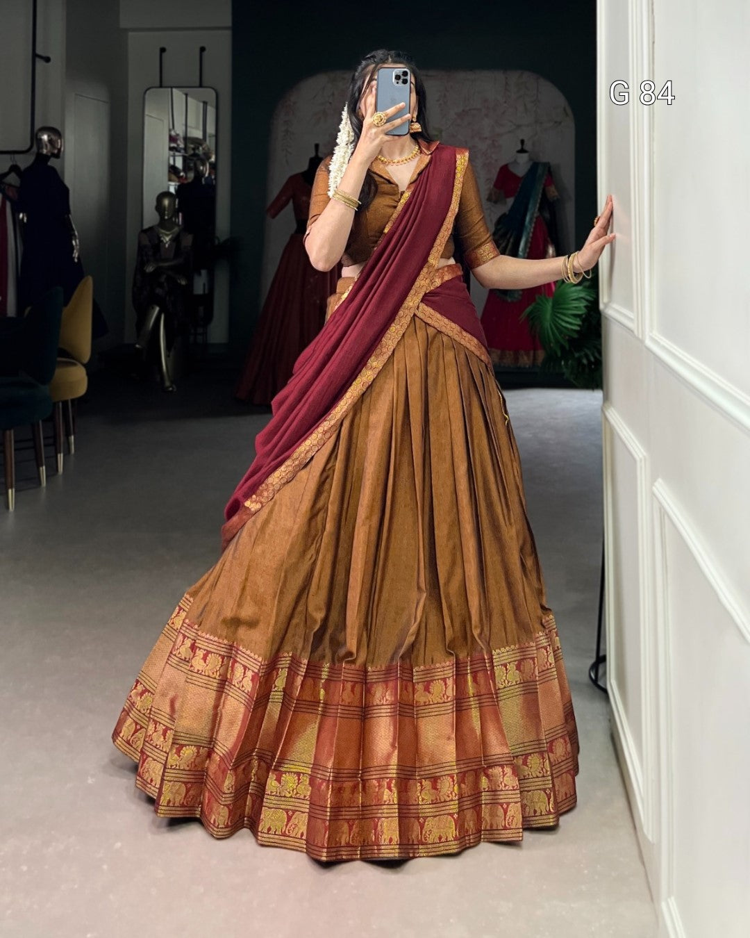 Woman wearing a traditional brown and red saree in a clothing store.
