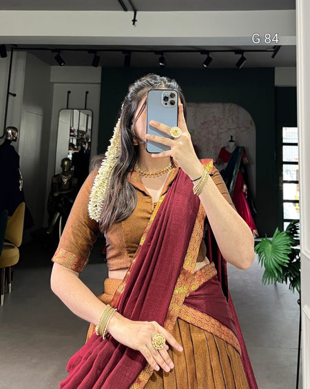 Person wearing a traditional maroon saree with gold border in an indoor setting.