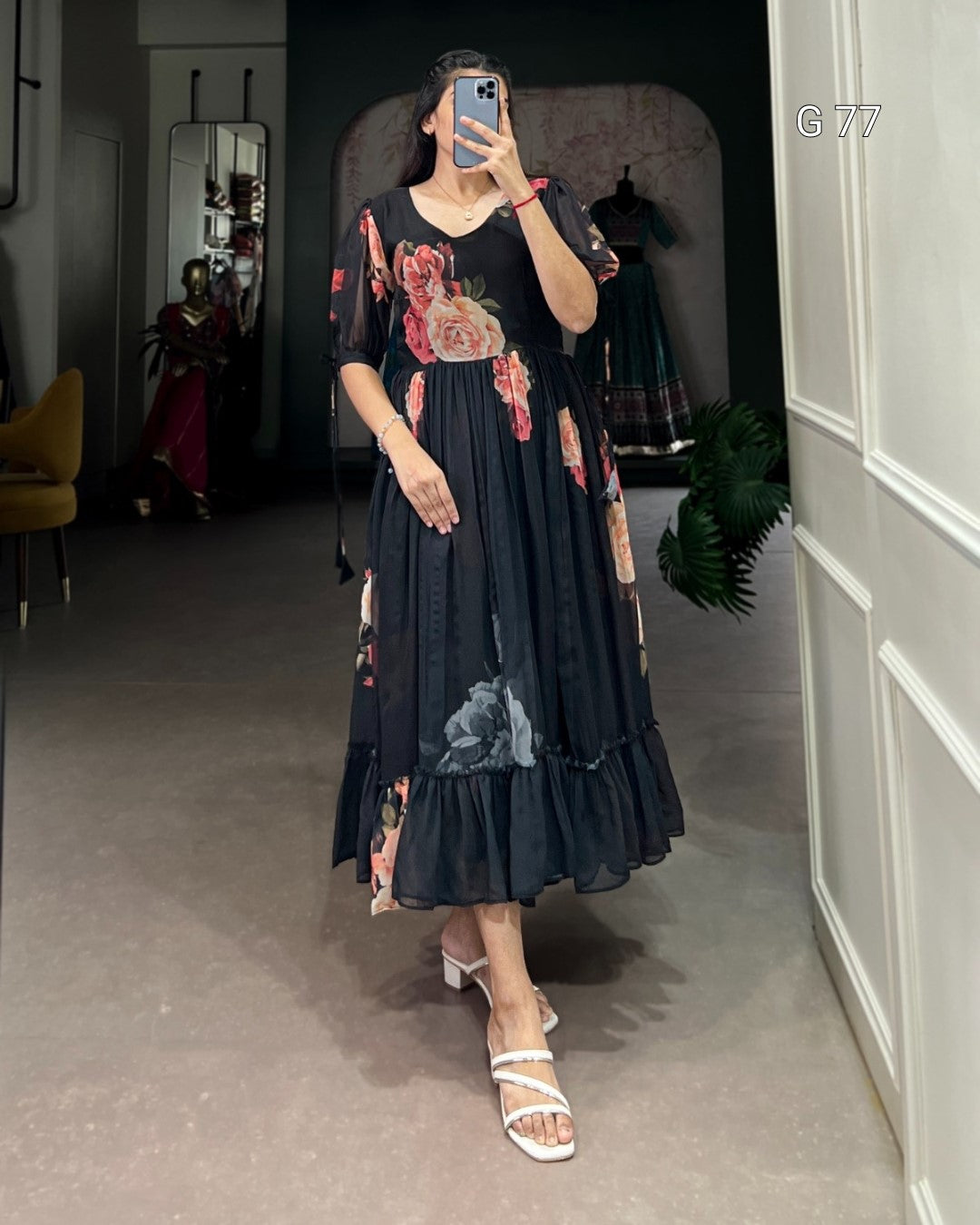 Woman wearing a dark floral dress in a room with a mirror.