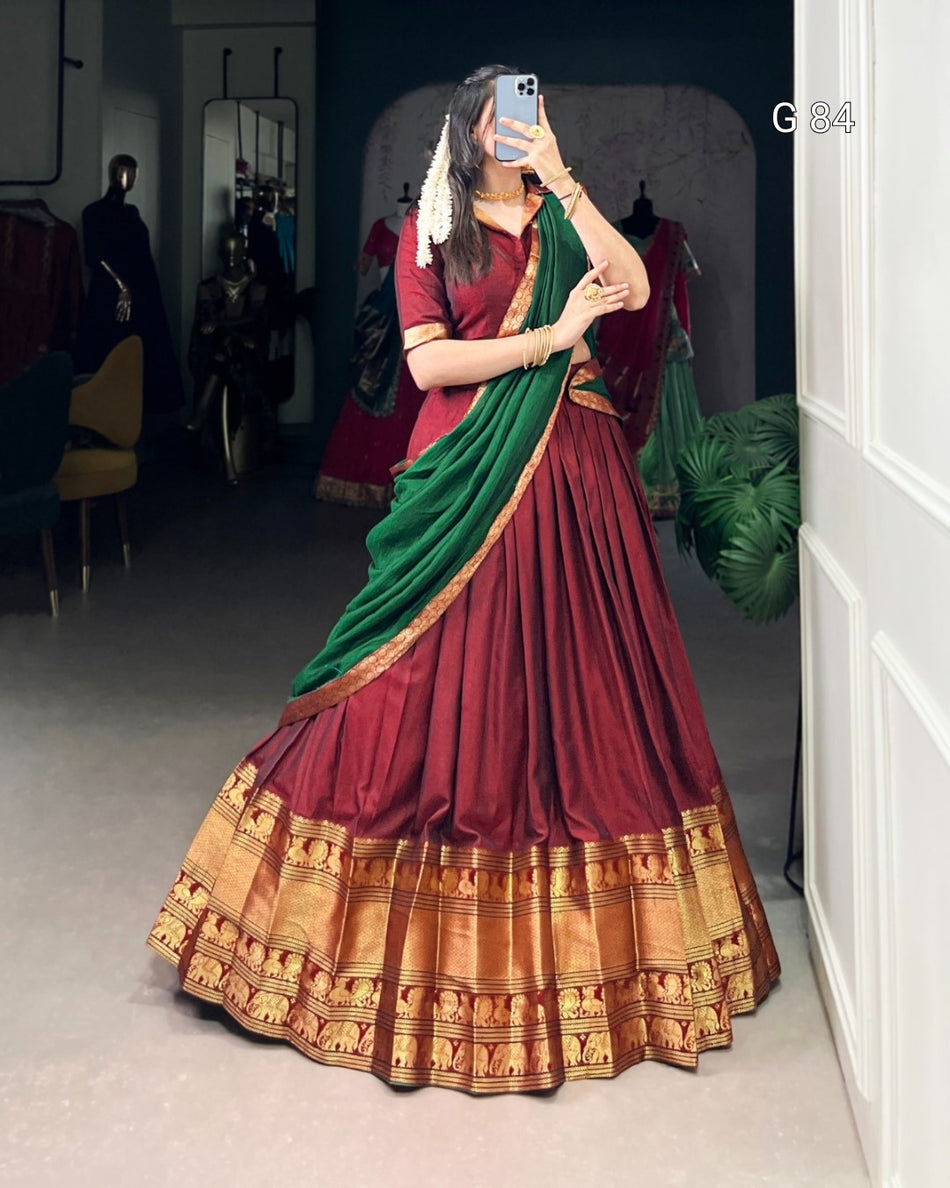 Woman wearing a traditional saree with a maroon and green design, standing in a room.
