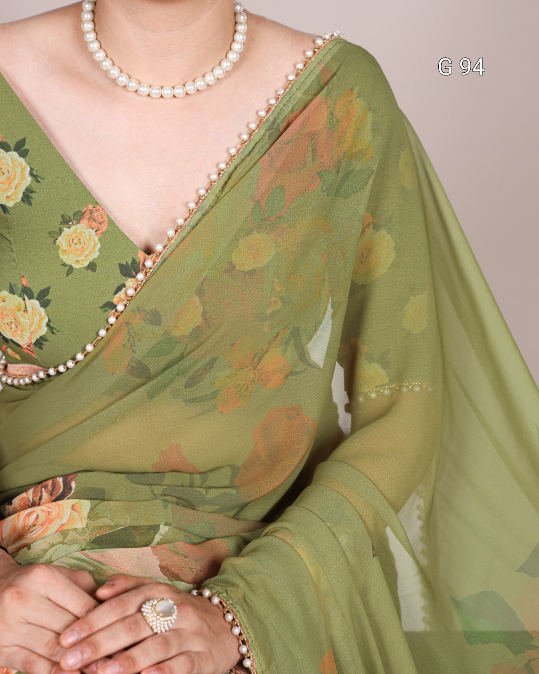 Green floral saree with a pearl border and jewelry on a neutral background
