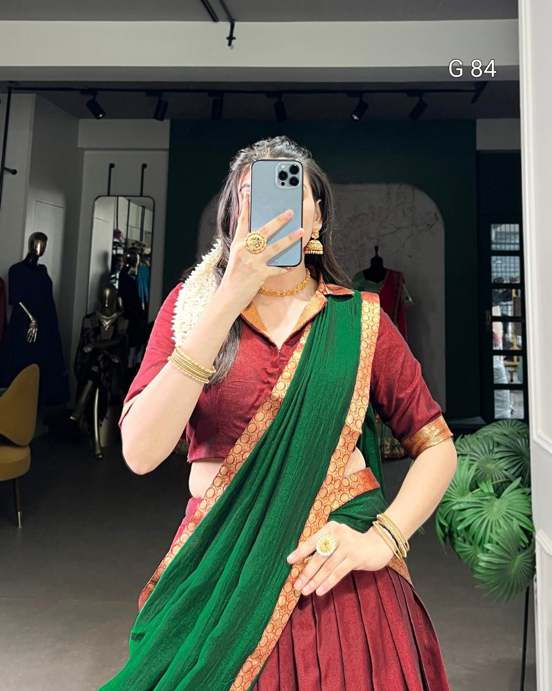Person wearing a green and red saree in a store setting