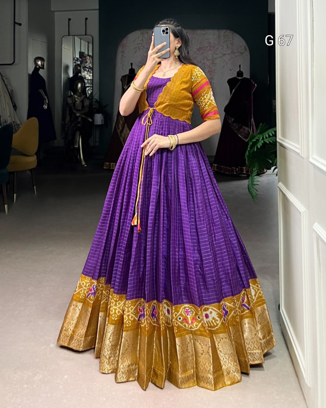 Woman wearing a purple and gold traditional outfit taking a mirror selfie.