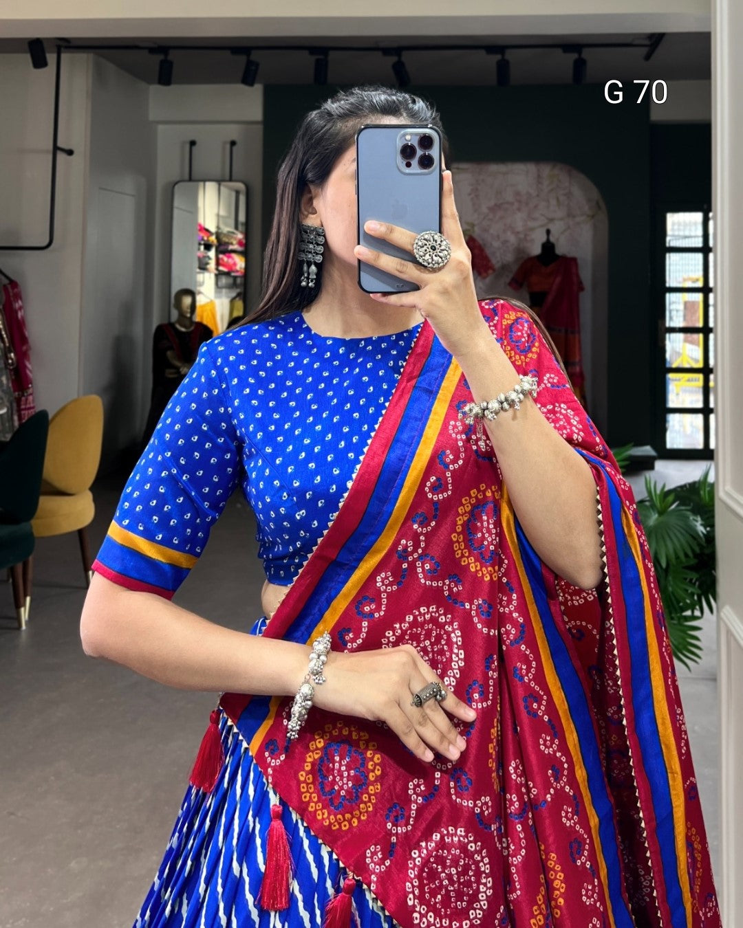 Person wearing a colorful saree with a blue blouse, taking a mirror selfie.