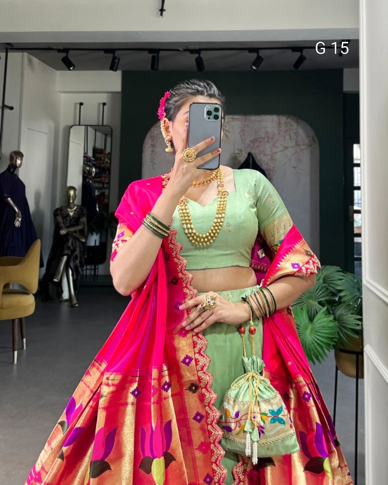 Person wearing a traditional outfit with a bright pink and green saree in an indoor setting.