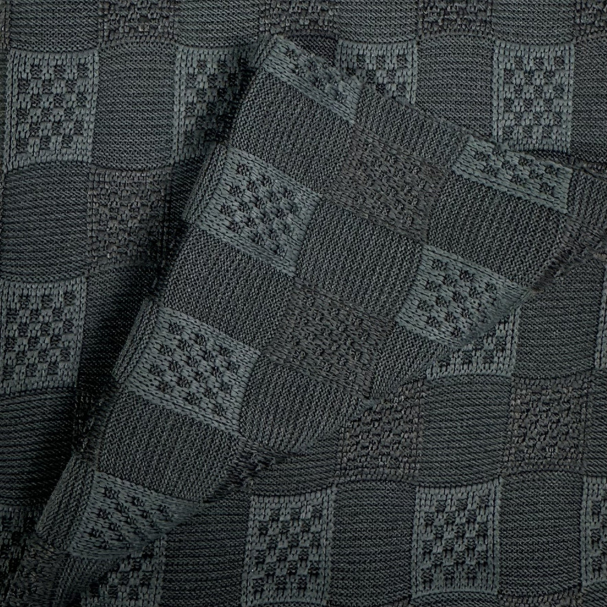 Close-up of a dark gray knitted fabric with a geometric pattern