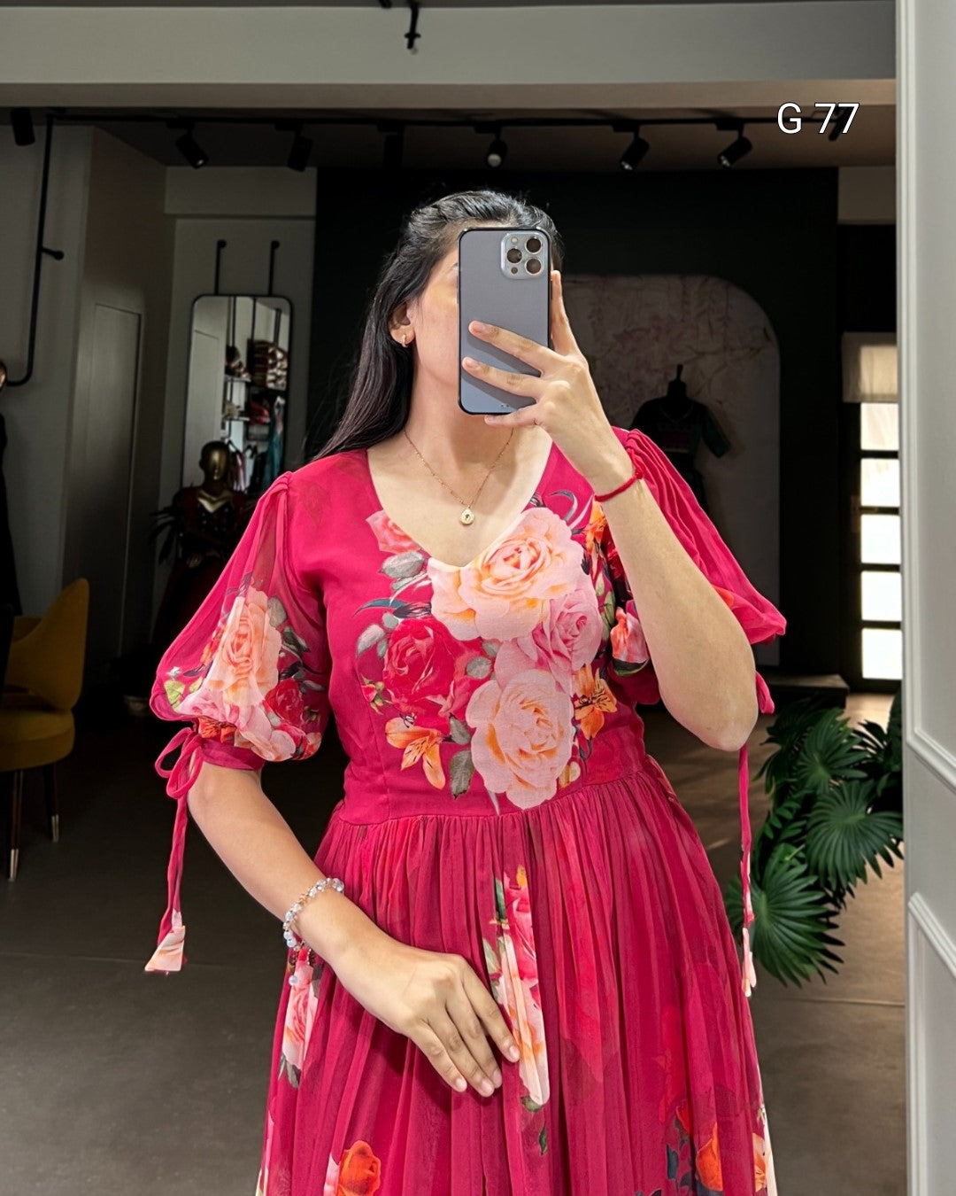 Person wearing a pink floral dress taking a mirror selfie.