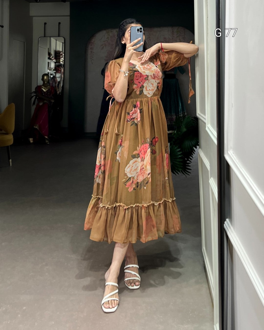 Woman taking a mirror selfie wearing a floral dress in a room.