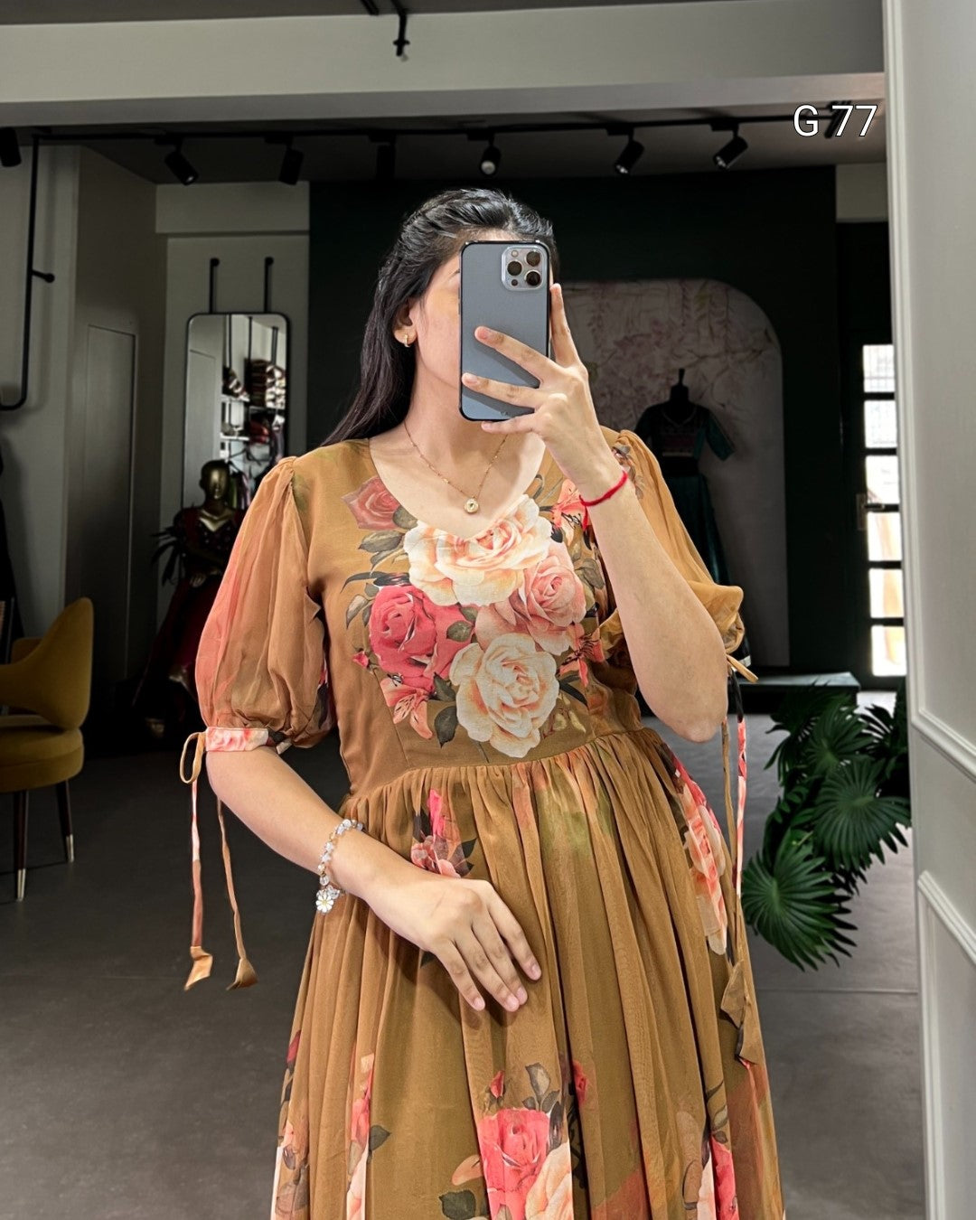 Woman taking a mirror selfie wearing a floral dress in an indoor setting.