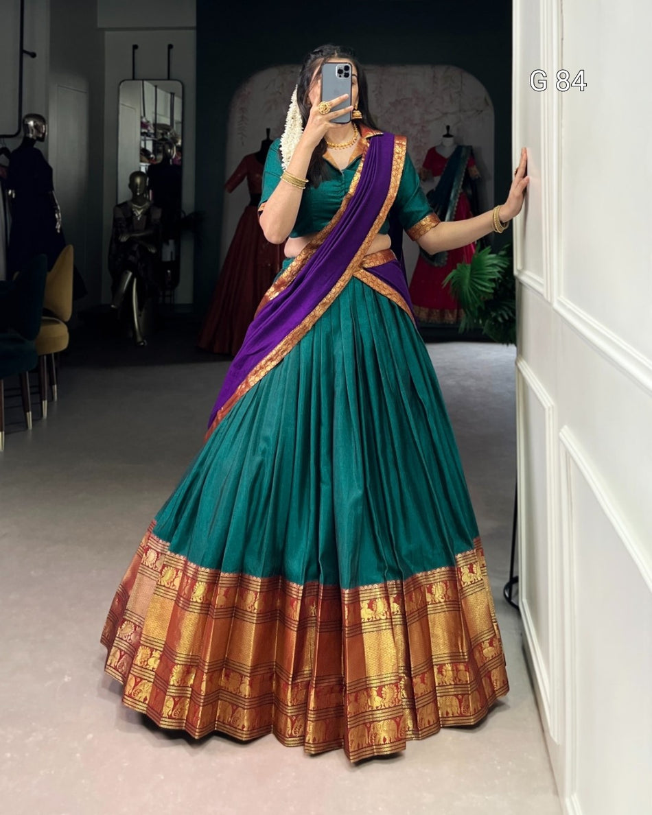 Woman wearing a teal and purple saree with gold border in a room.