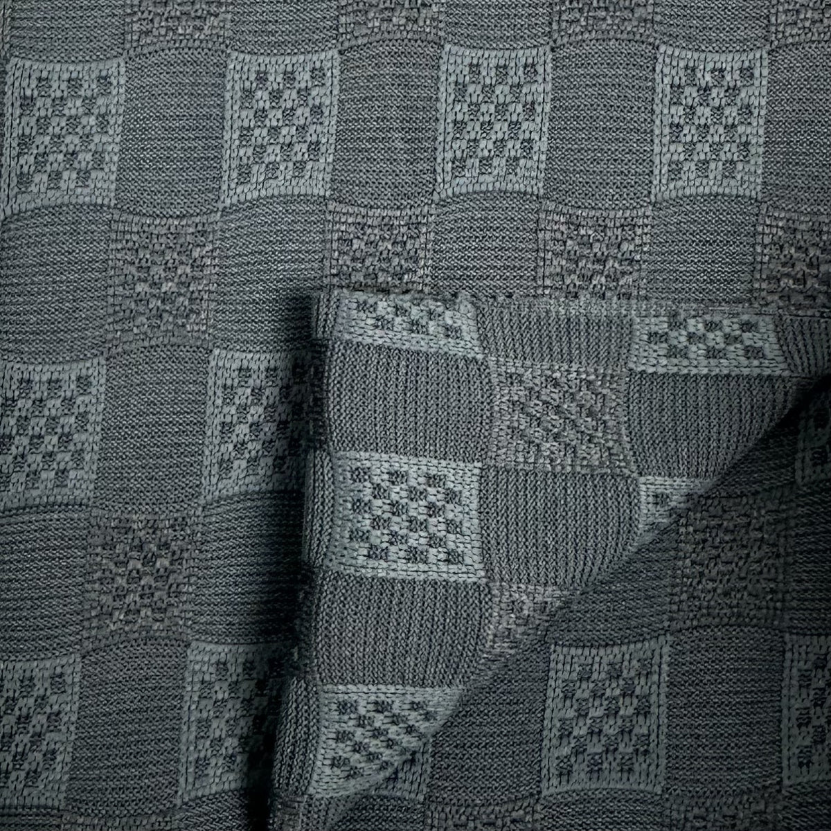 Textured fabric with a geometric pattern in shades of gray.