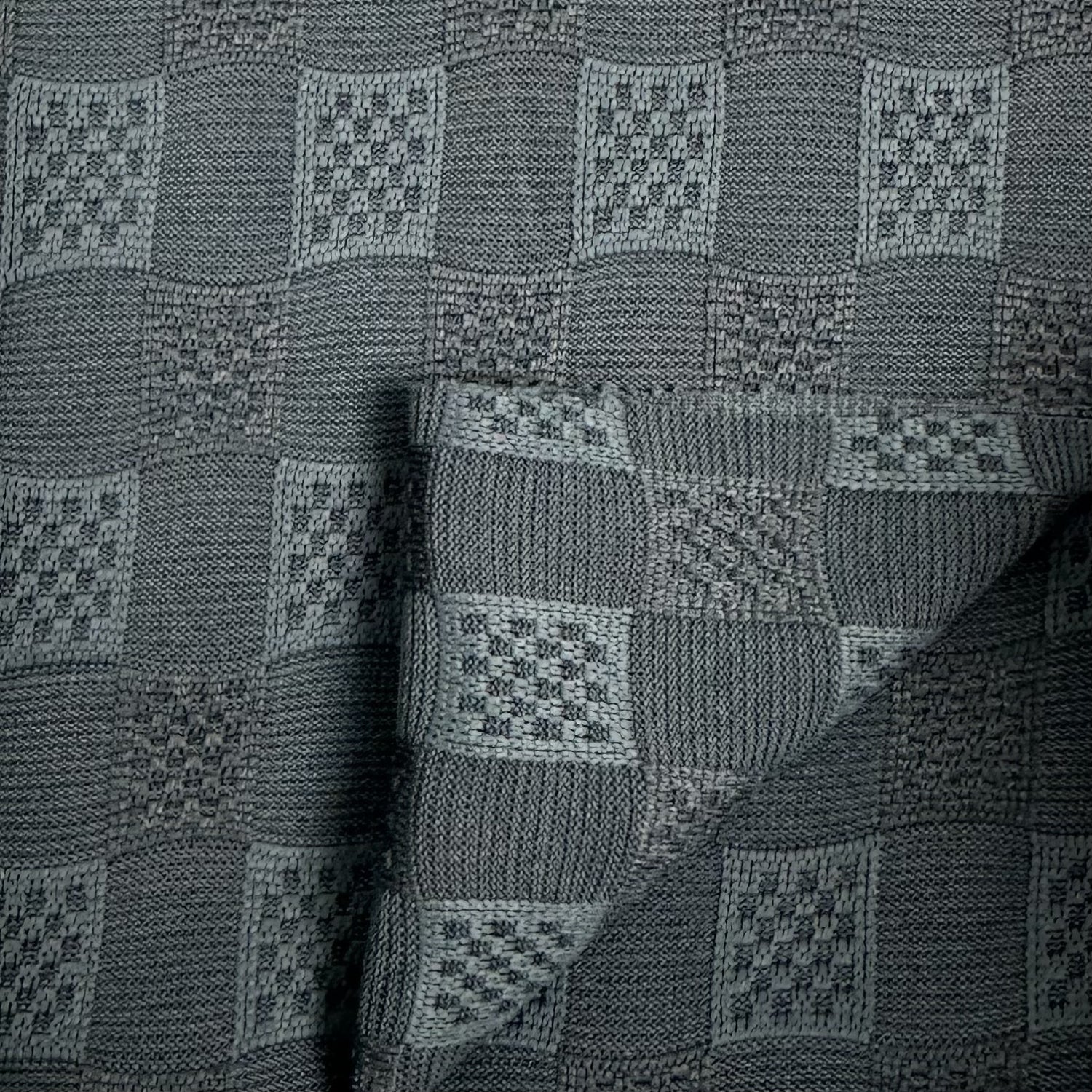 Textured fabric with a geometric pattern in shades of gray.