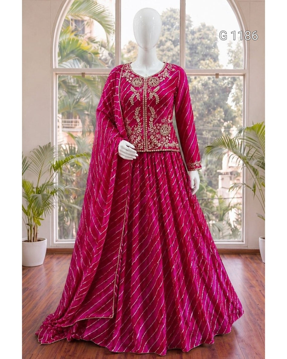 A magenta pink traditional Indian dress set with gold embroidery and striped pattern, displayed on a white mannequin in front of a large window.