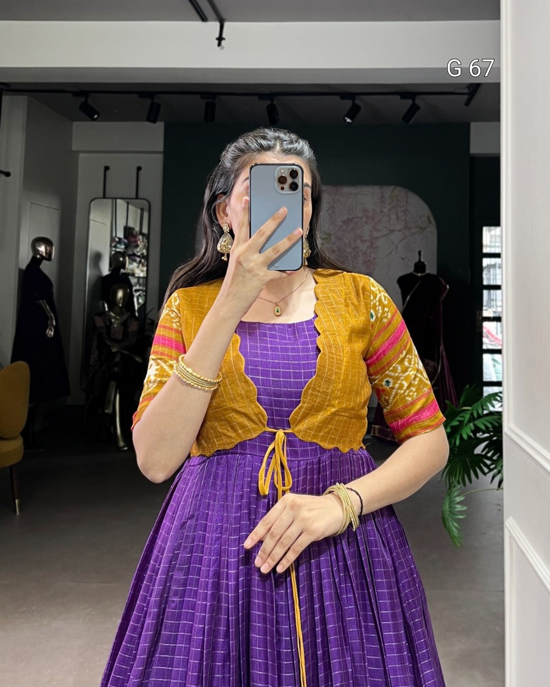 Person wearing a mustard yellow top and purple checkered dress in a store setting.