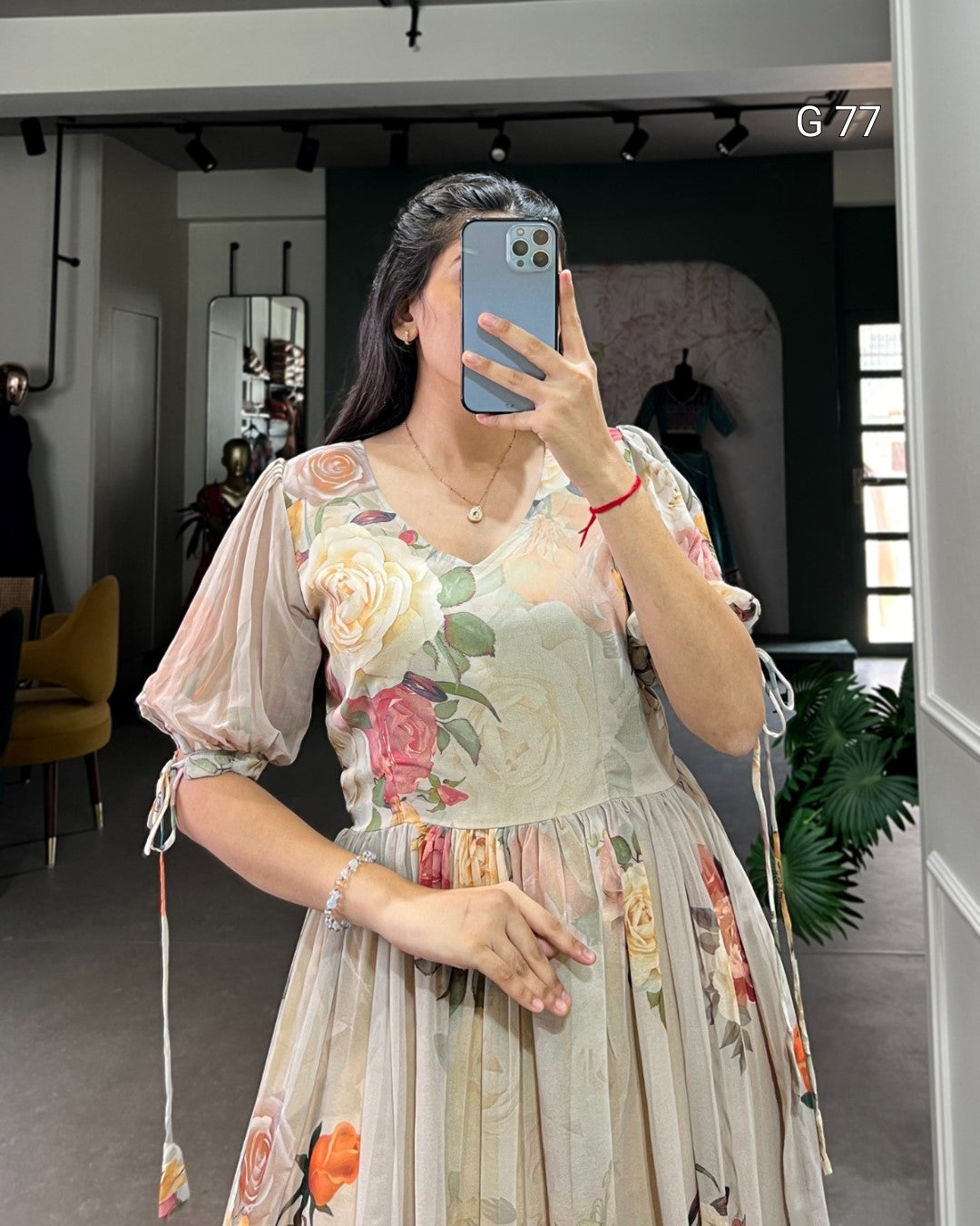 Woman taking a mirror selfie wearing a floral dress in an indoor setting.