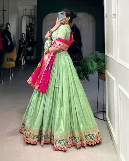 Person wearing a light green traditional outfit with colorful accents in a room.