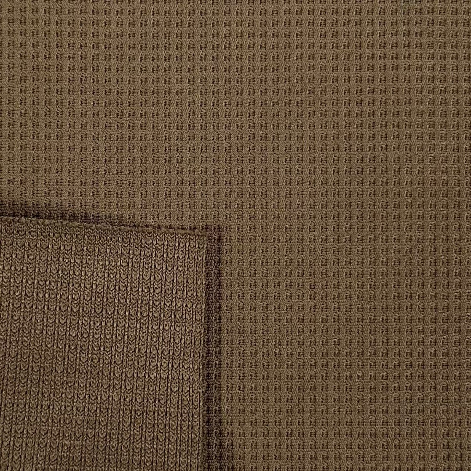 Close-up of brown textured fabric with a visible seam.