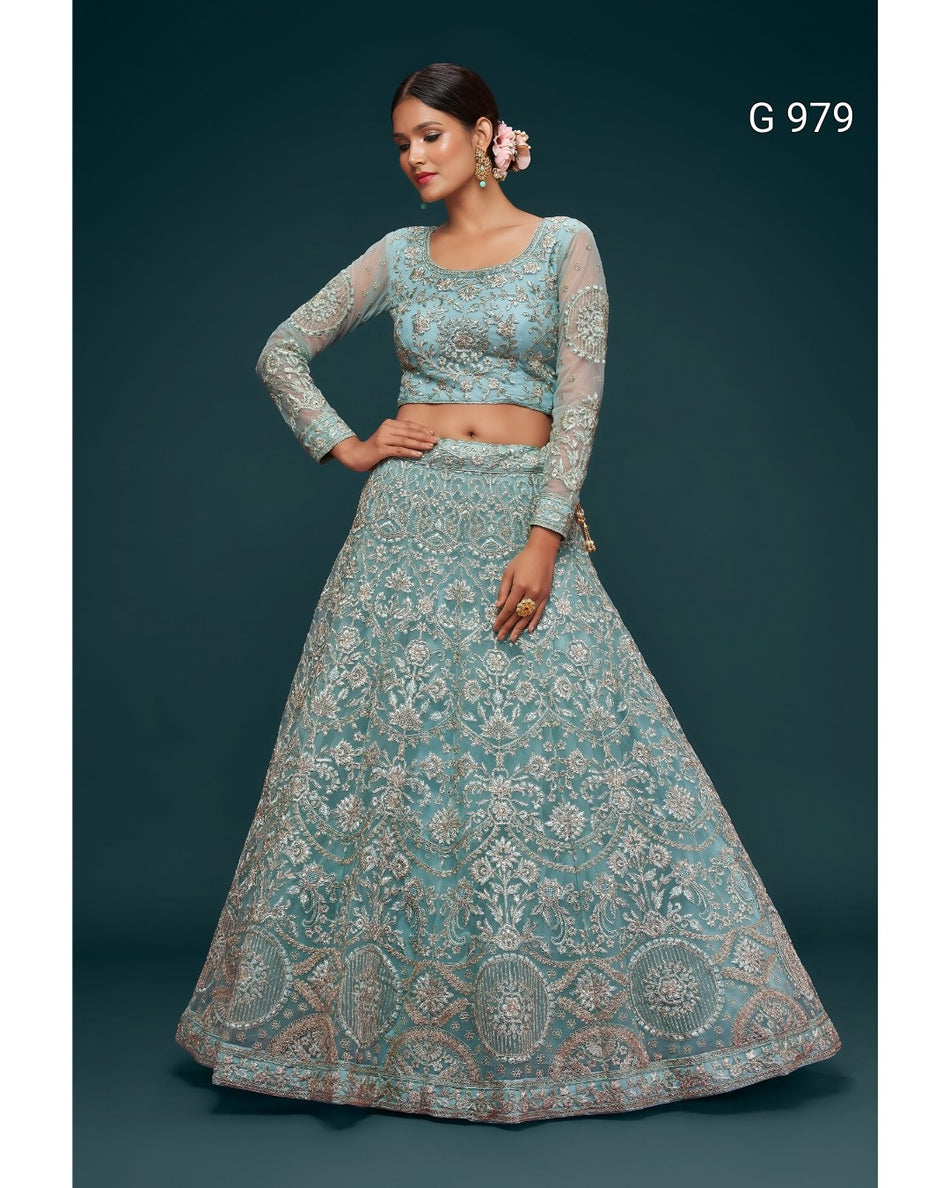 A woman modeling a light blue-green lehenga choli set with intricate silver and gold embroidery, set against a dark teal background. The text 'G 979' is visible in the top right corner.