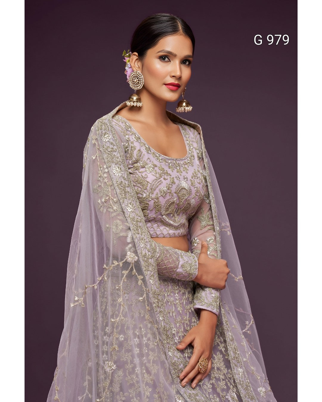 A woman modeling a lavender and silver embroidered traditional outfit with a sheer draped overlay, set against a solid dark purple background. The text 'G 979' is visible in the top right corner.