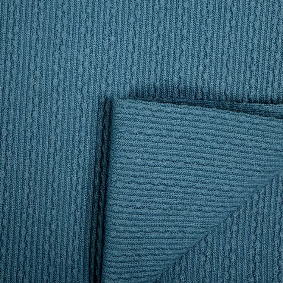 Close-up of textured teal fabric with a subtle pattern