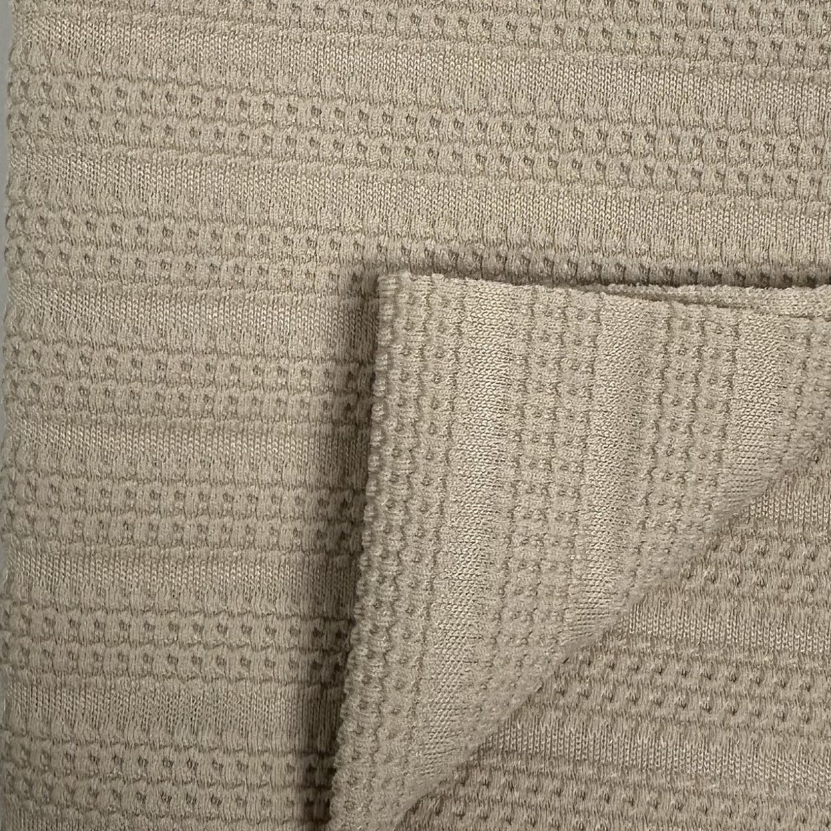Close-up of textured beige fabric with a waffle pattern