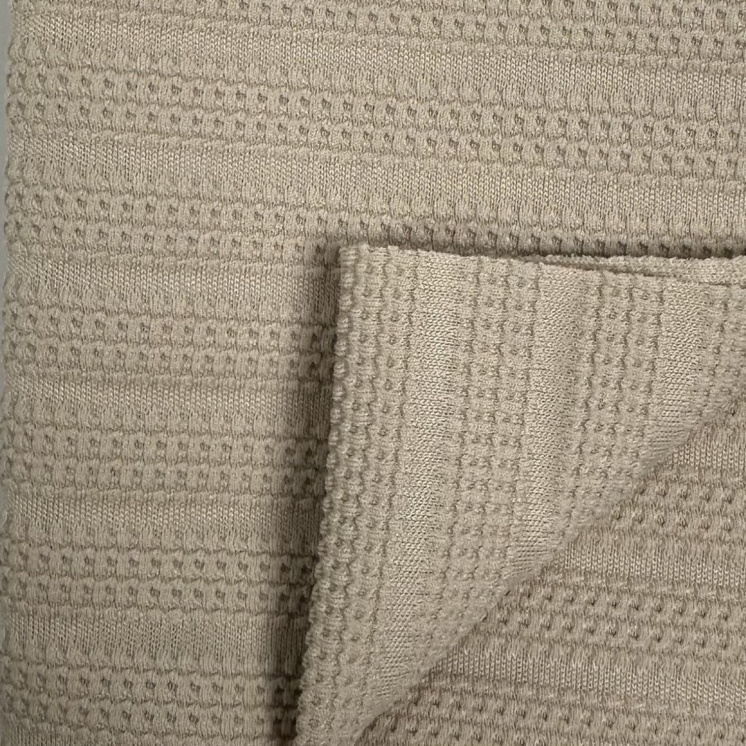Close-up of textured beige fabric with a waffle pattern