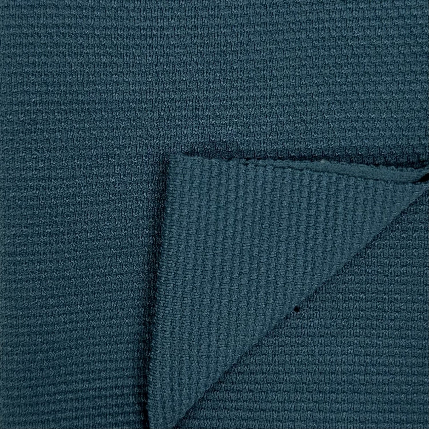 Close-up of textured teal fabric with a corner folded over