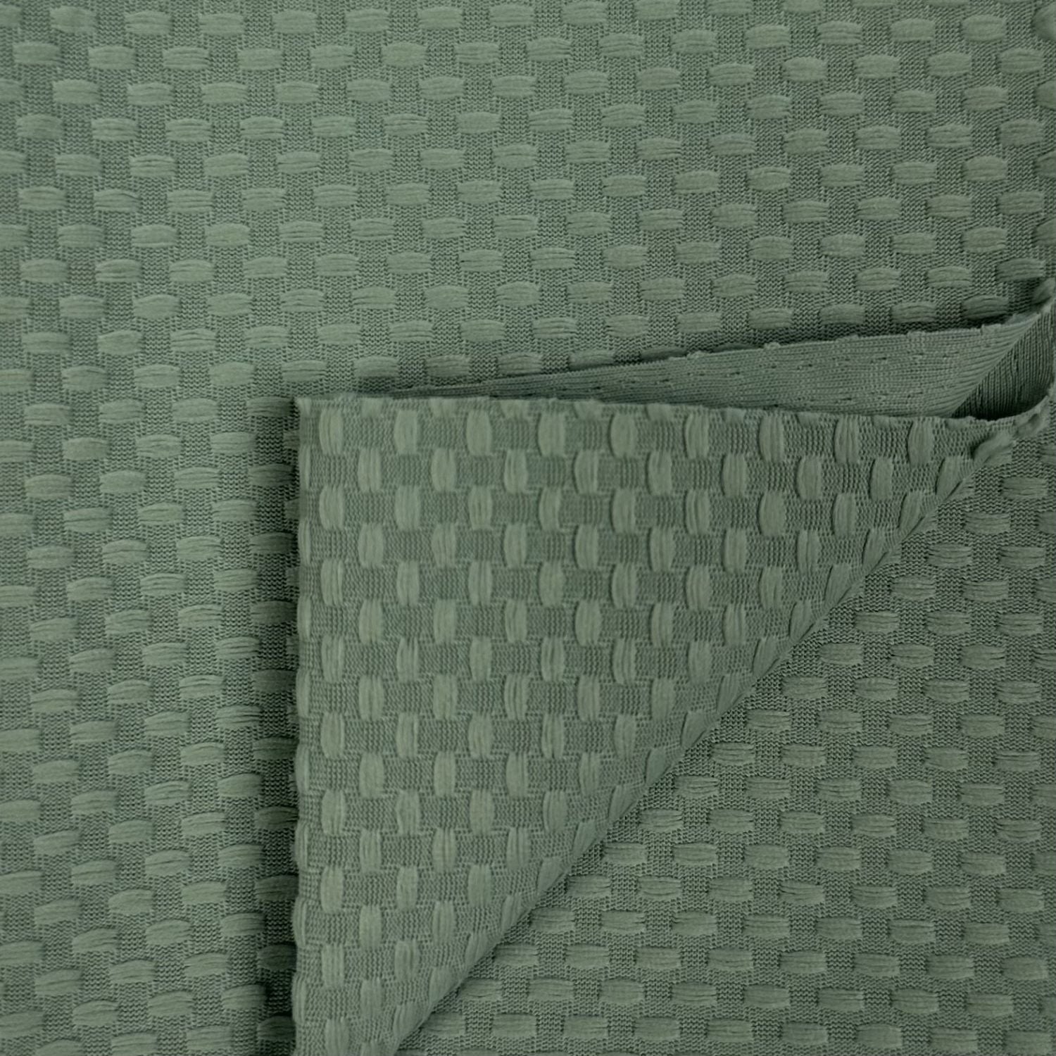 Folded green fabric with a textured pattern on a matching background