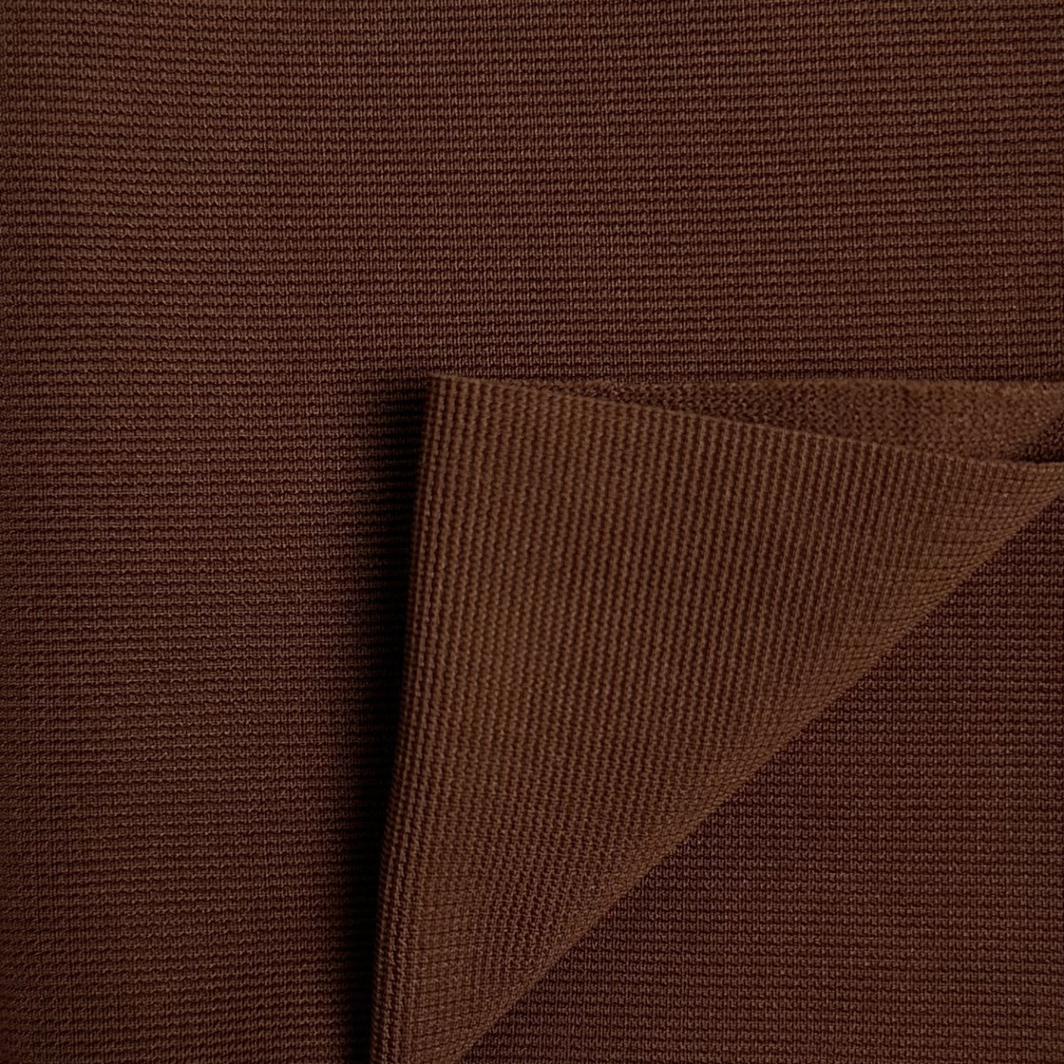 Close-up of brown textured fabric with a folded corner