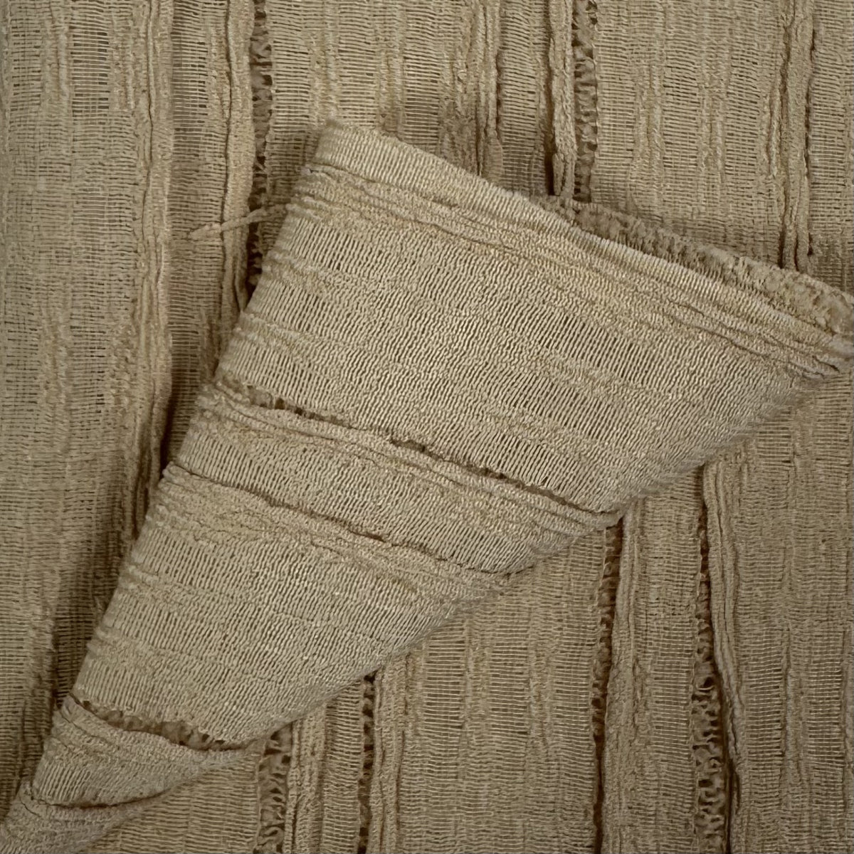 Close-up of beige textured fabric with a folded corner