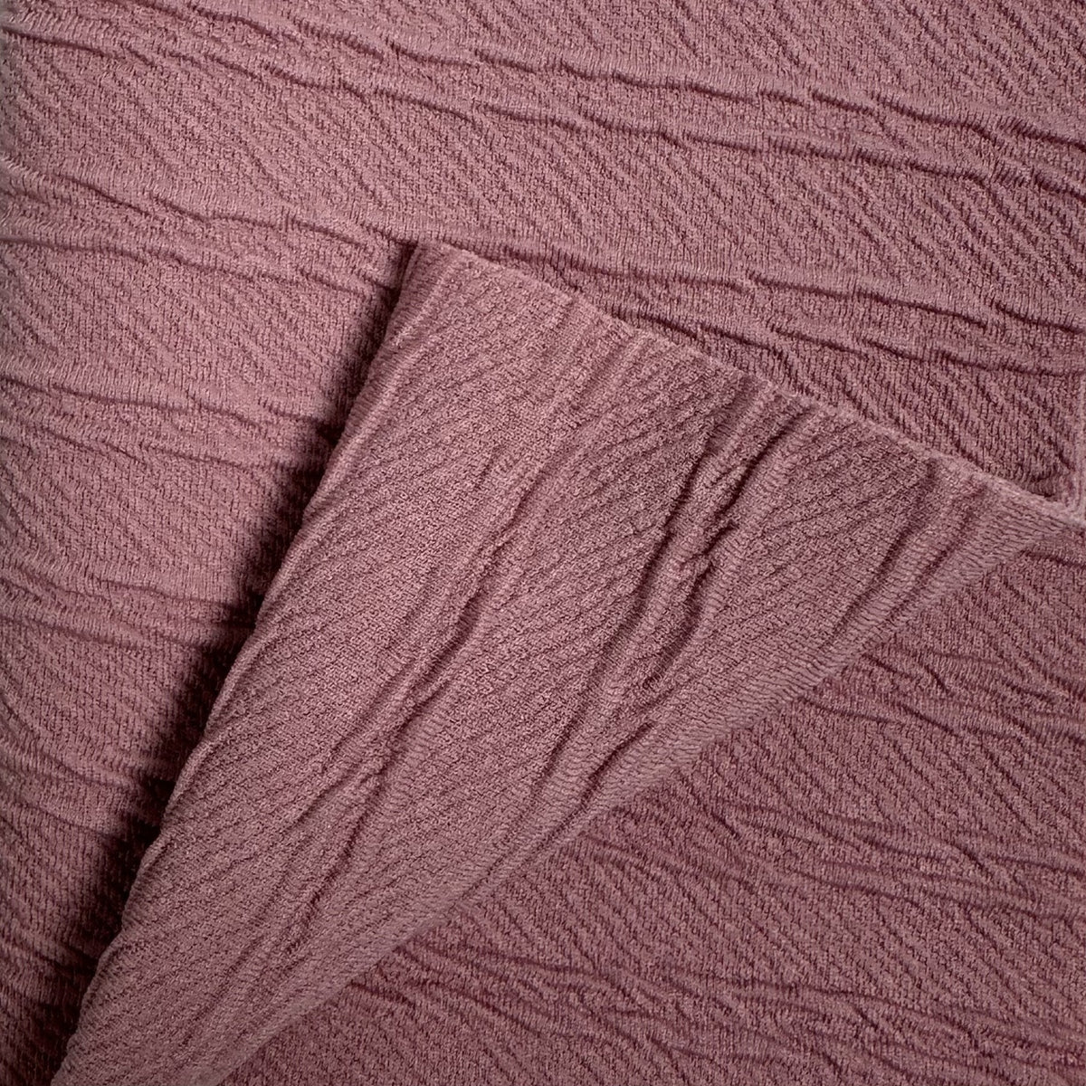 Close-up of textured mauve fabric with a focus on pattern and texture.