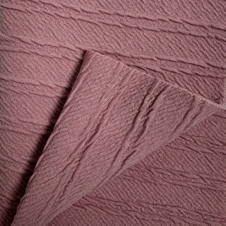 Close-up of textured mauve fabric with a focus on pattern and texture.