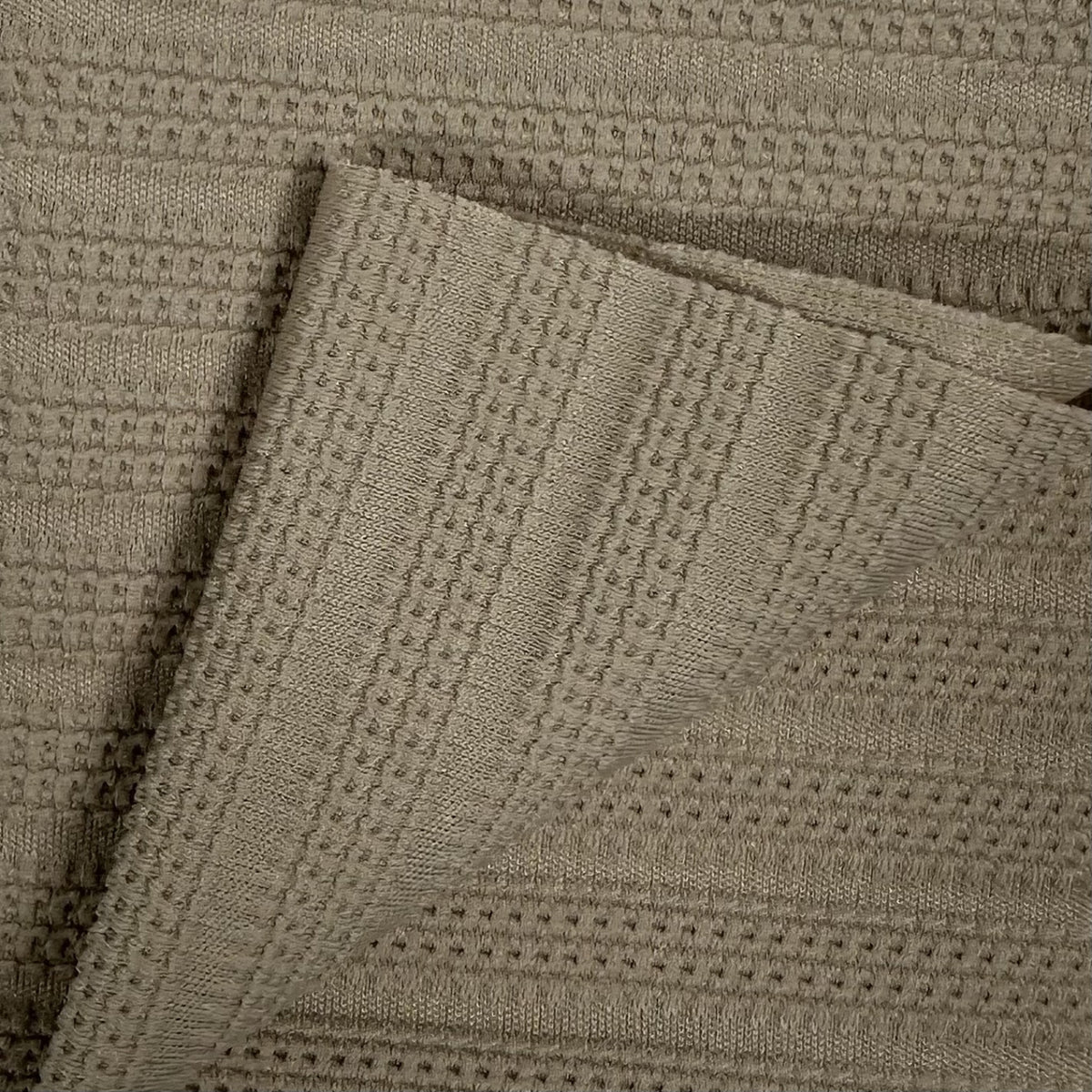 Close-up of a textured beige fabric with a diamond pattern