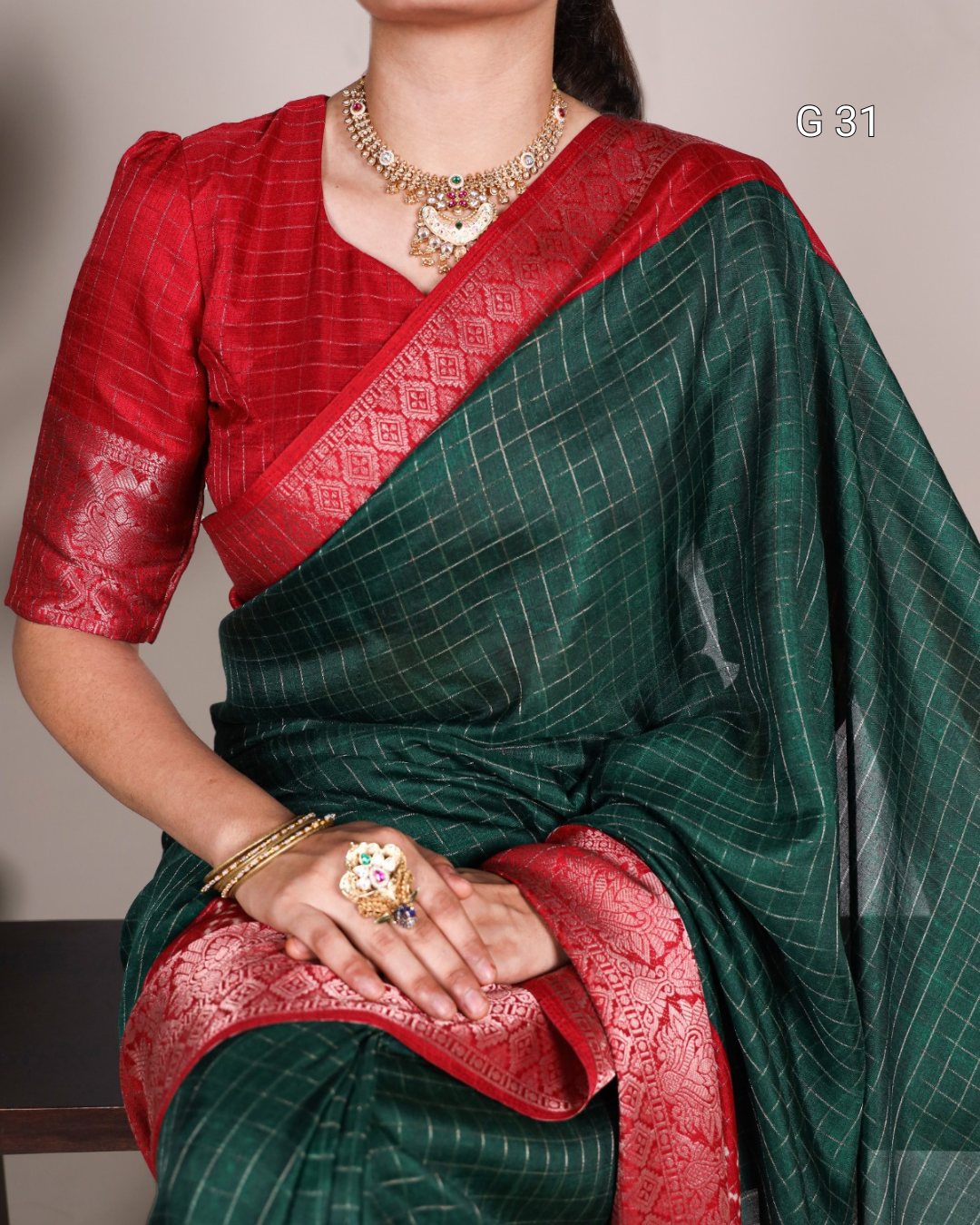 Woman wearing a green saree with red border and jewelry