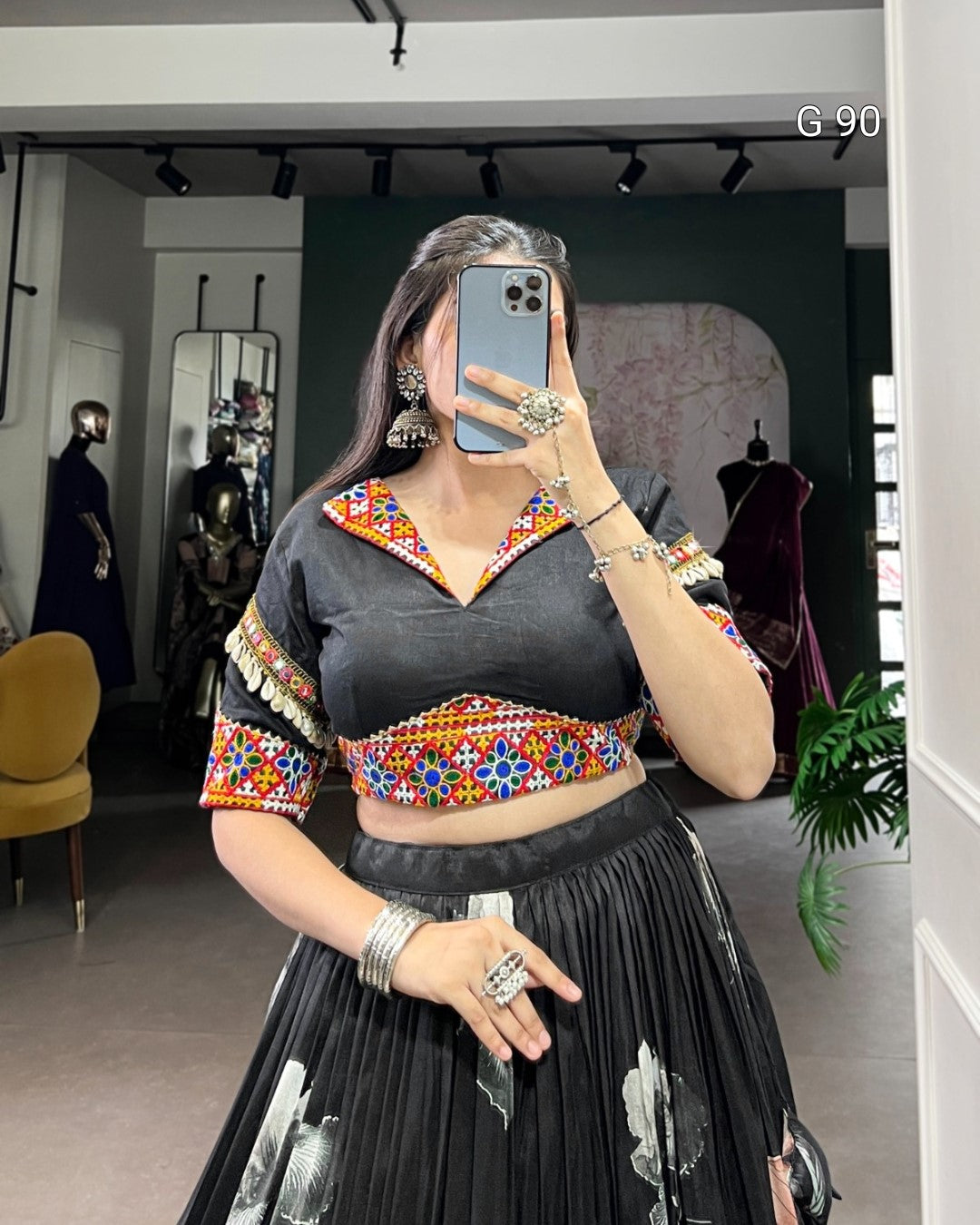Person wearing a black outfit with colorful embroidery in a store setting