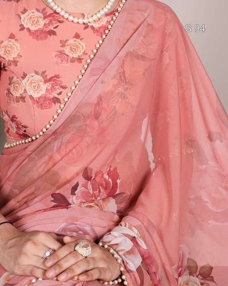 Pink floral saree with a pearl border and jewelry.