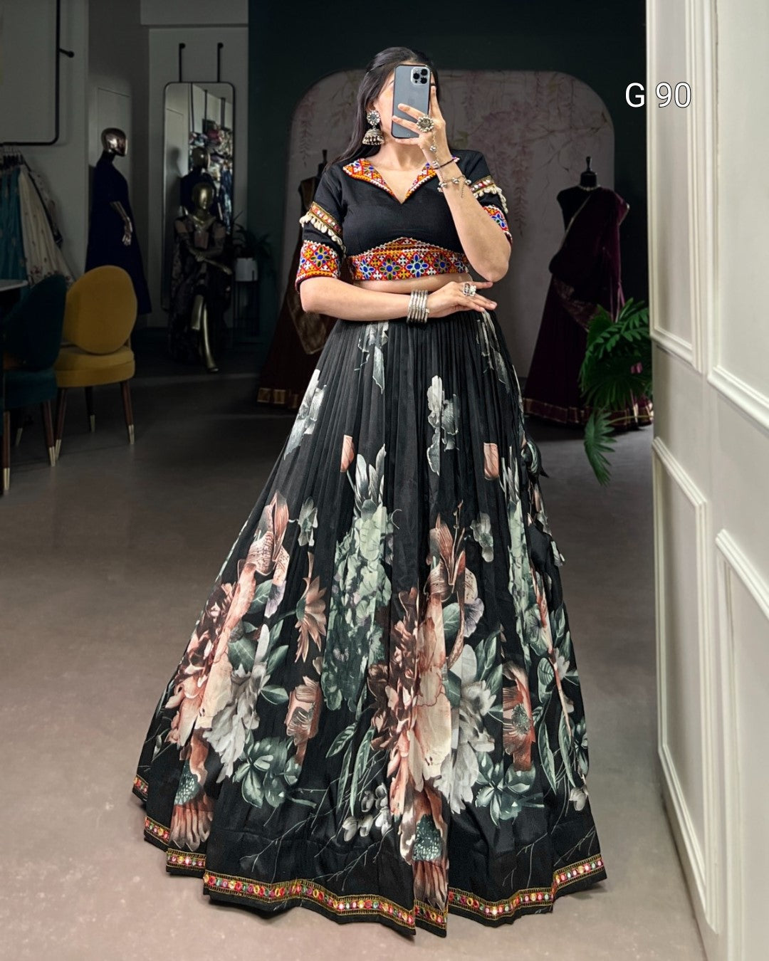 Woman wearing a black floral dress in a room with mirrors and furniture.