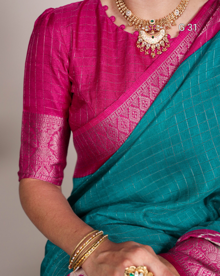 Teal saree with pink blouse and gold jewelry on a neutral background