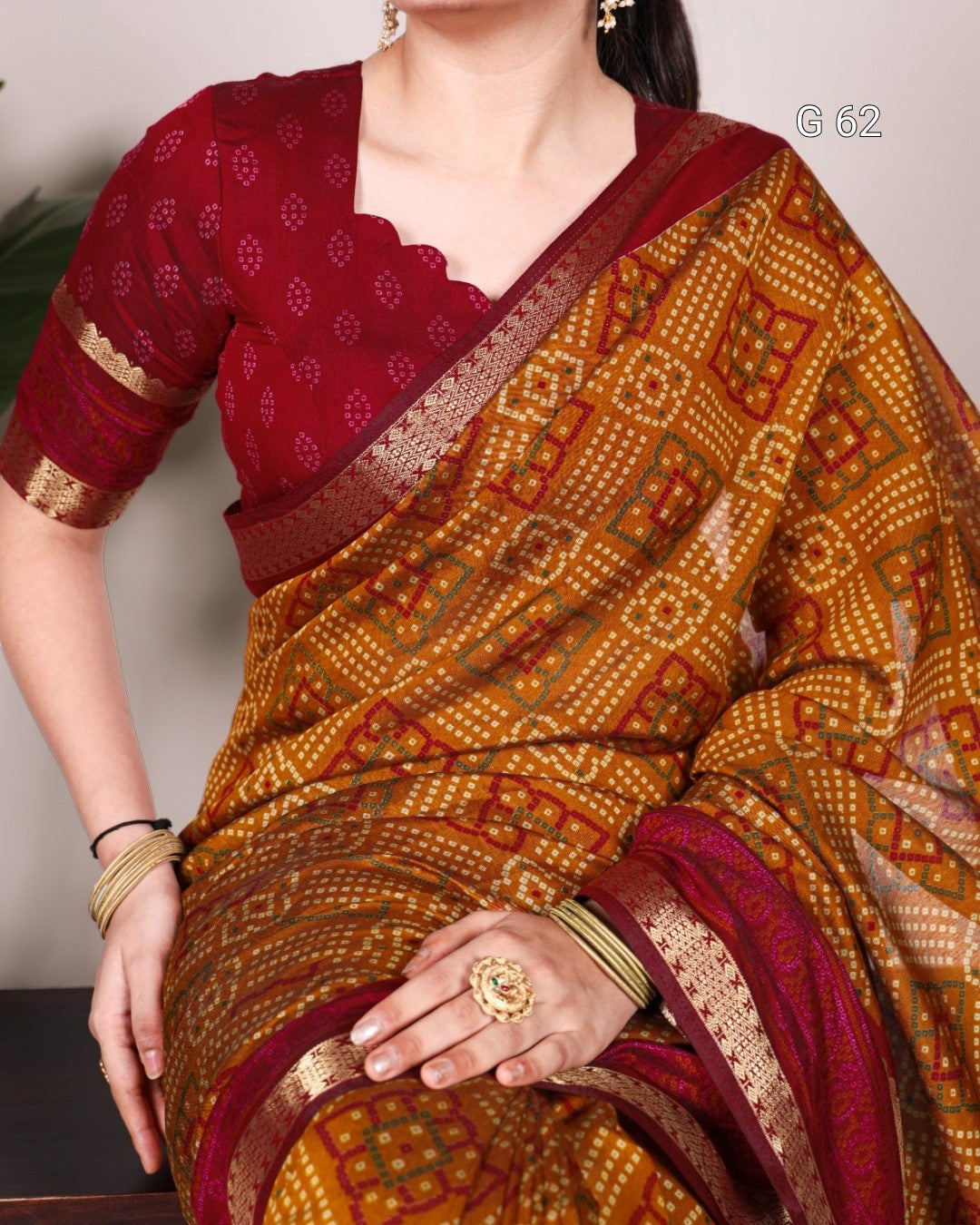 Woman wearing a traditional maroon and gold saree with a patterned blouse.