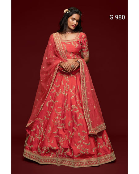 A woman modeling a traditional red lehenga choli set with gold embroidery, featuring a red skirt, matching blouse, and dupatta, set against a dark red background with the text 'G 980' in the top right.