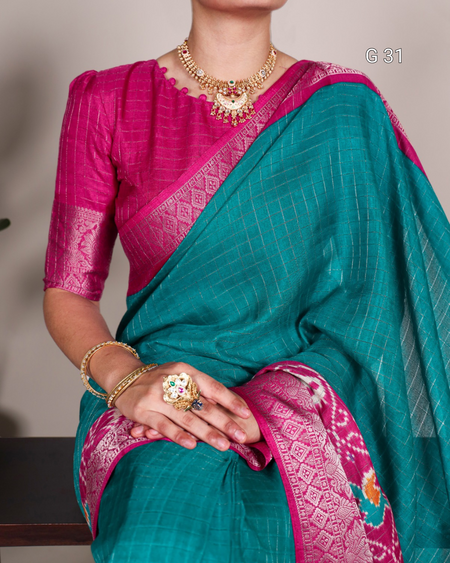 Teal and pink saree with jewelry on a neutral background