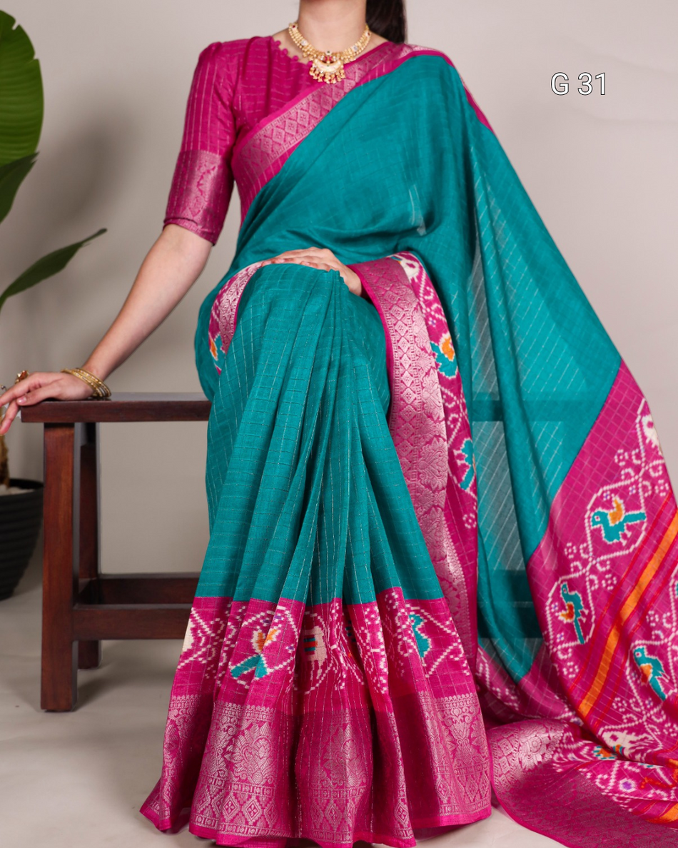 Teal and pink saree with a patterned border, worn by a person, on a neutral background.