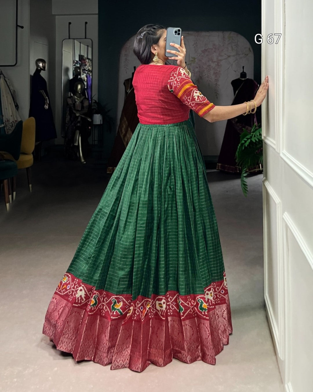 Person wearing a red and green traditional outfit taking a mirror selfie.