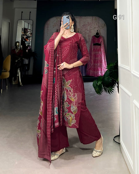 Woman in a maroon traditional outfit with floral patterns in a room.