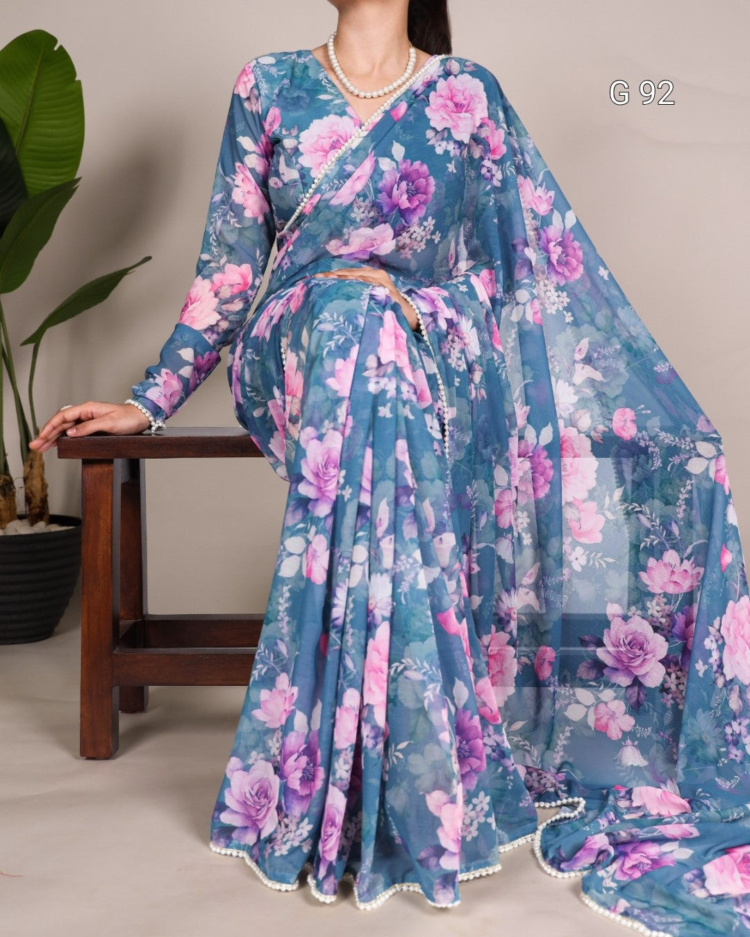 Woman wearing a blue floral saree with a plain background