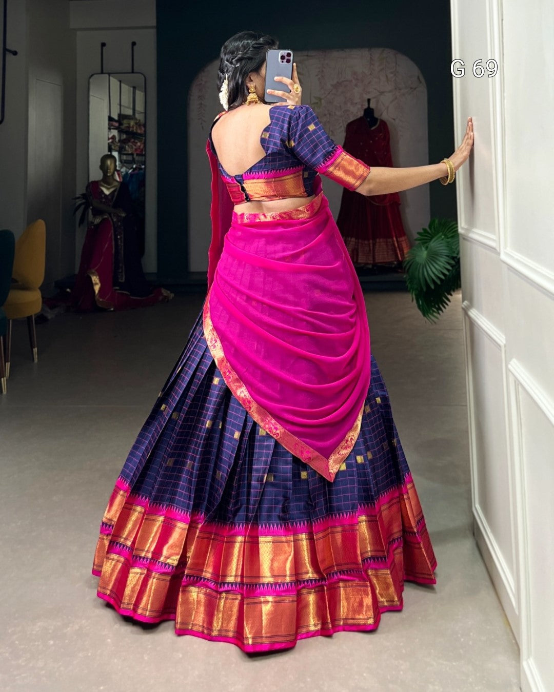 Person wearing a traditional saree with a pink blouse in a room.
