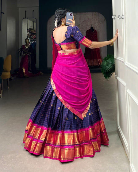 Person wearing a traditional saree with a pink blouse in a room.